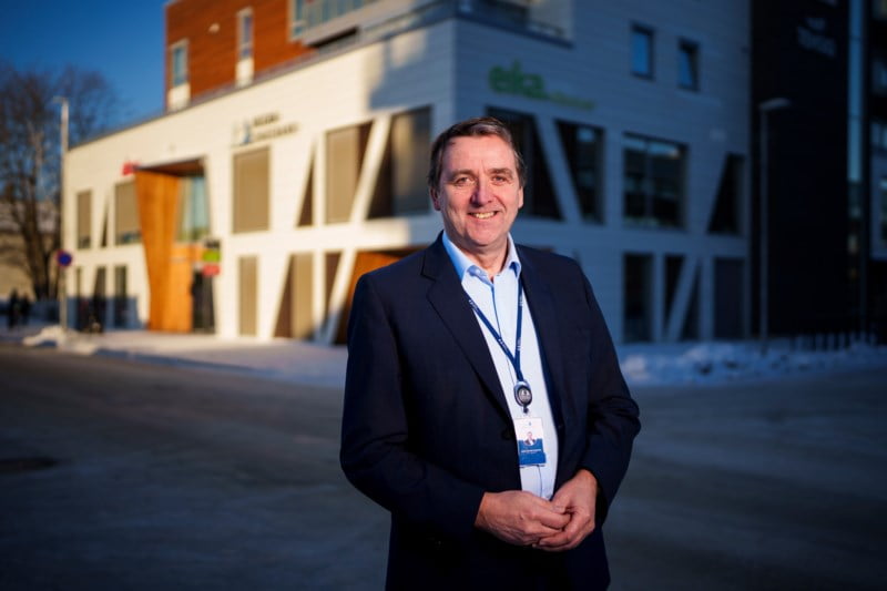 En fornøyd mann i dress står foran Finanshuset Hegra Sparebank og smiler til kameraet med hendene foldet