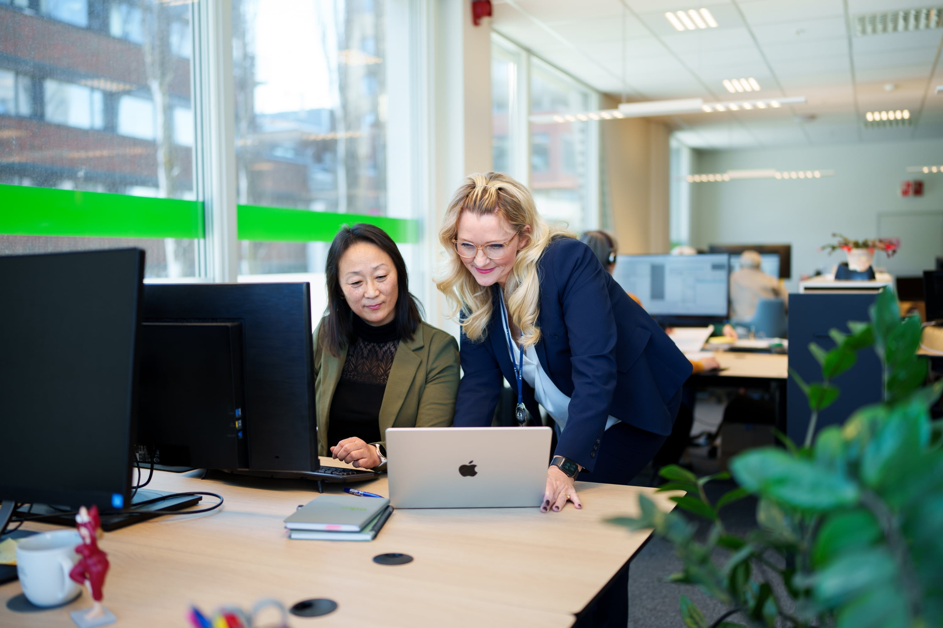 En sittende kvinne blir assistert av en blond kvinne i dress