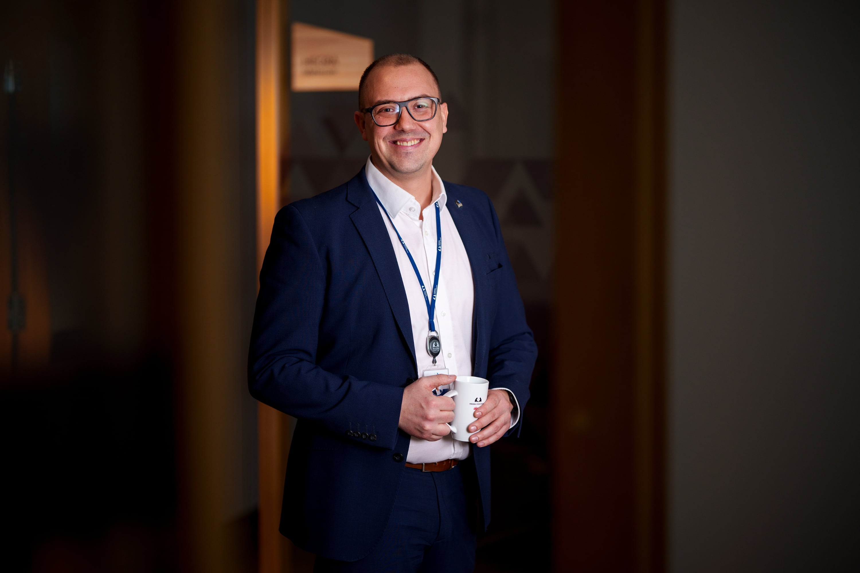 En fornøyd bankarbeider iført dress ser rett inn i kameraet mens han smiler