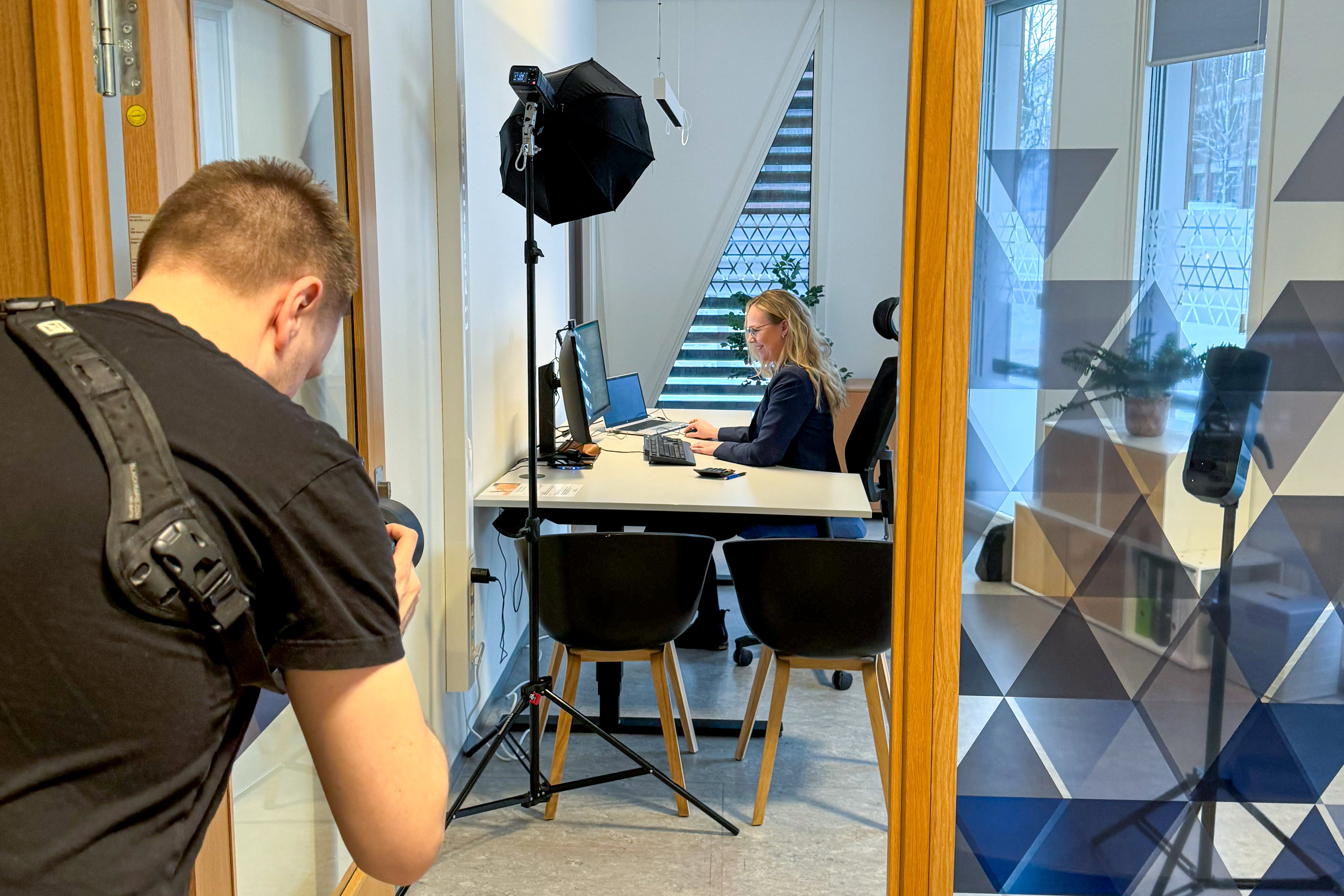 En mann i venstre i bilde tar bilde av en sparerådgiver forran pcen