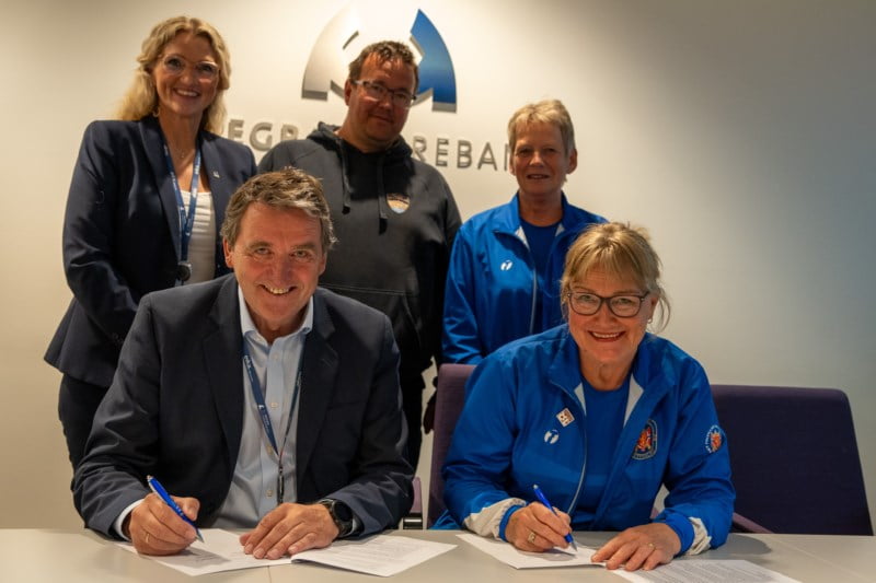 Hegra skytehall signerer kontrakt med Hegra Sparebank. Her sitter de og ser mot kamera mens de signerer avtalen og smiler.