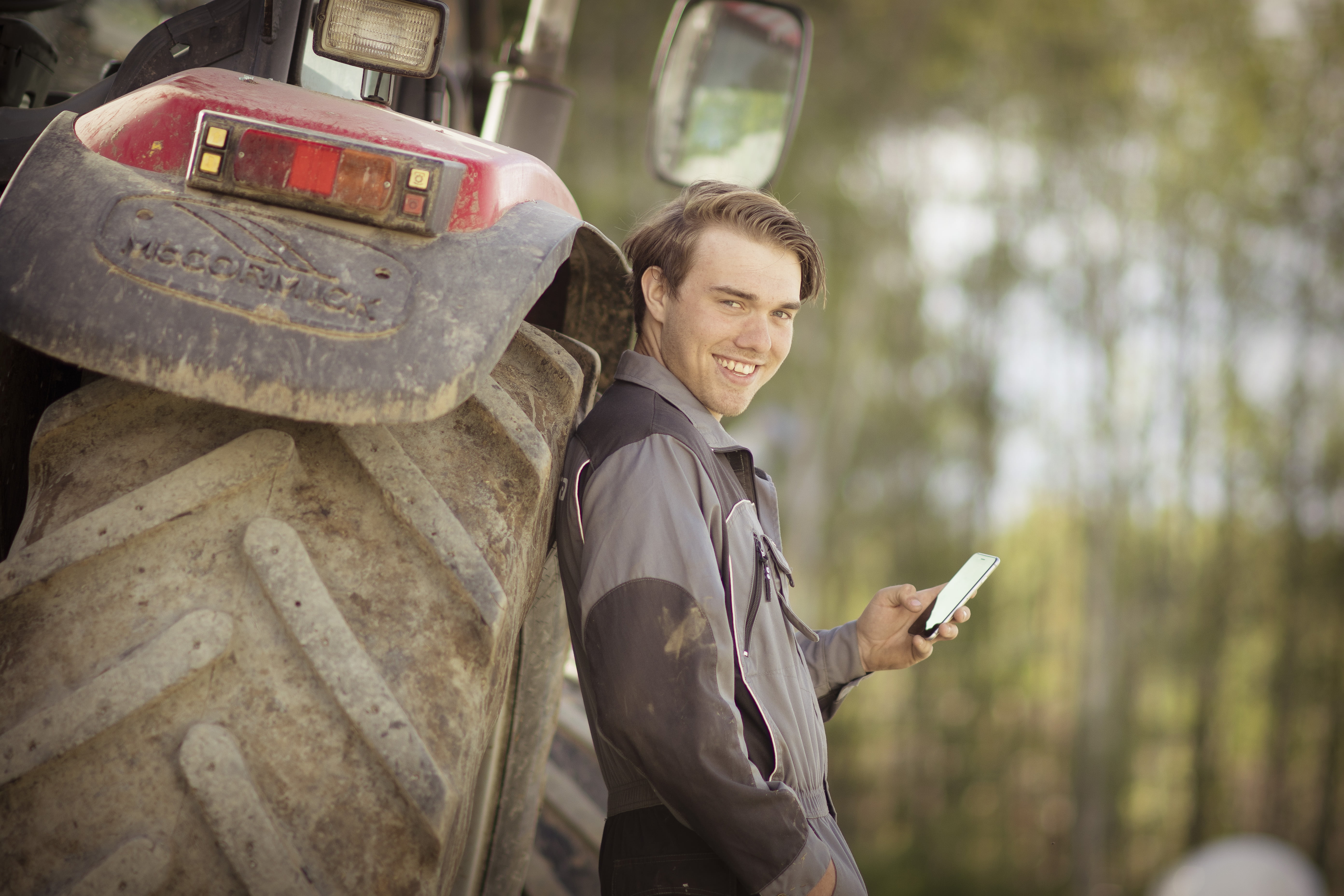 En ung mann står med ryggen til en traktor
