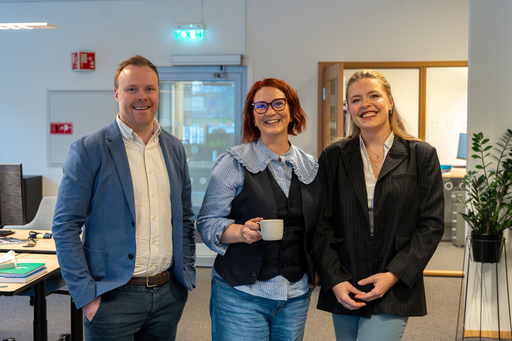 Tre ansatte ved Eika Økonomi Midt-Norge smiler mot kamera - situasjonsbilde triangel park