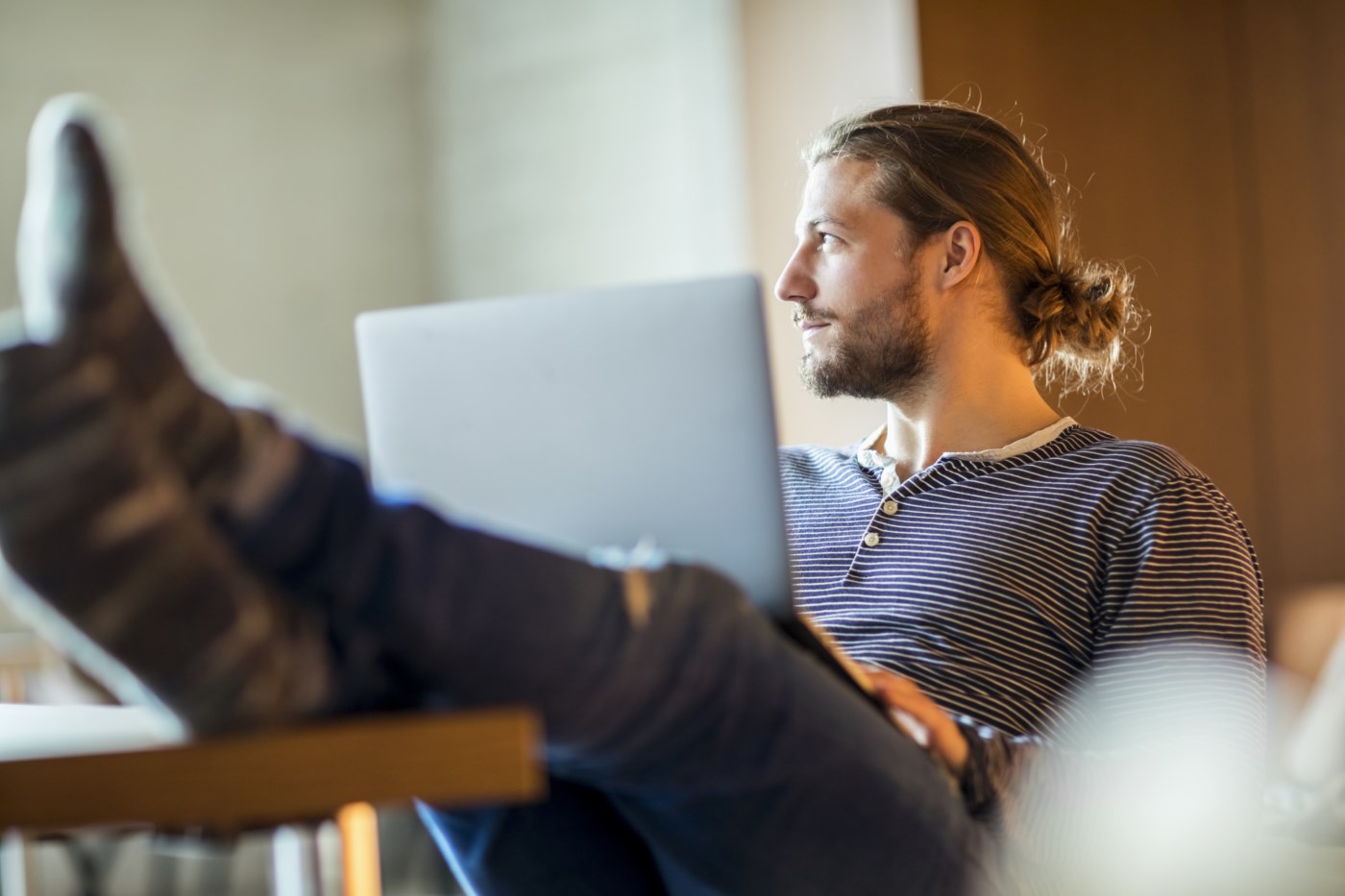 Mann med laptop og beina på bordet