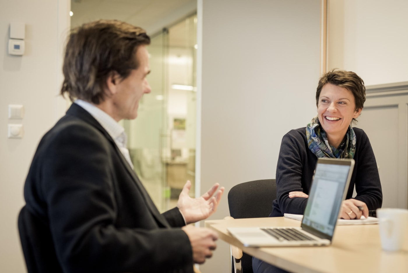 Dame og mann prater sammen på møterom. foto